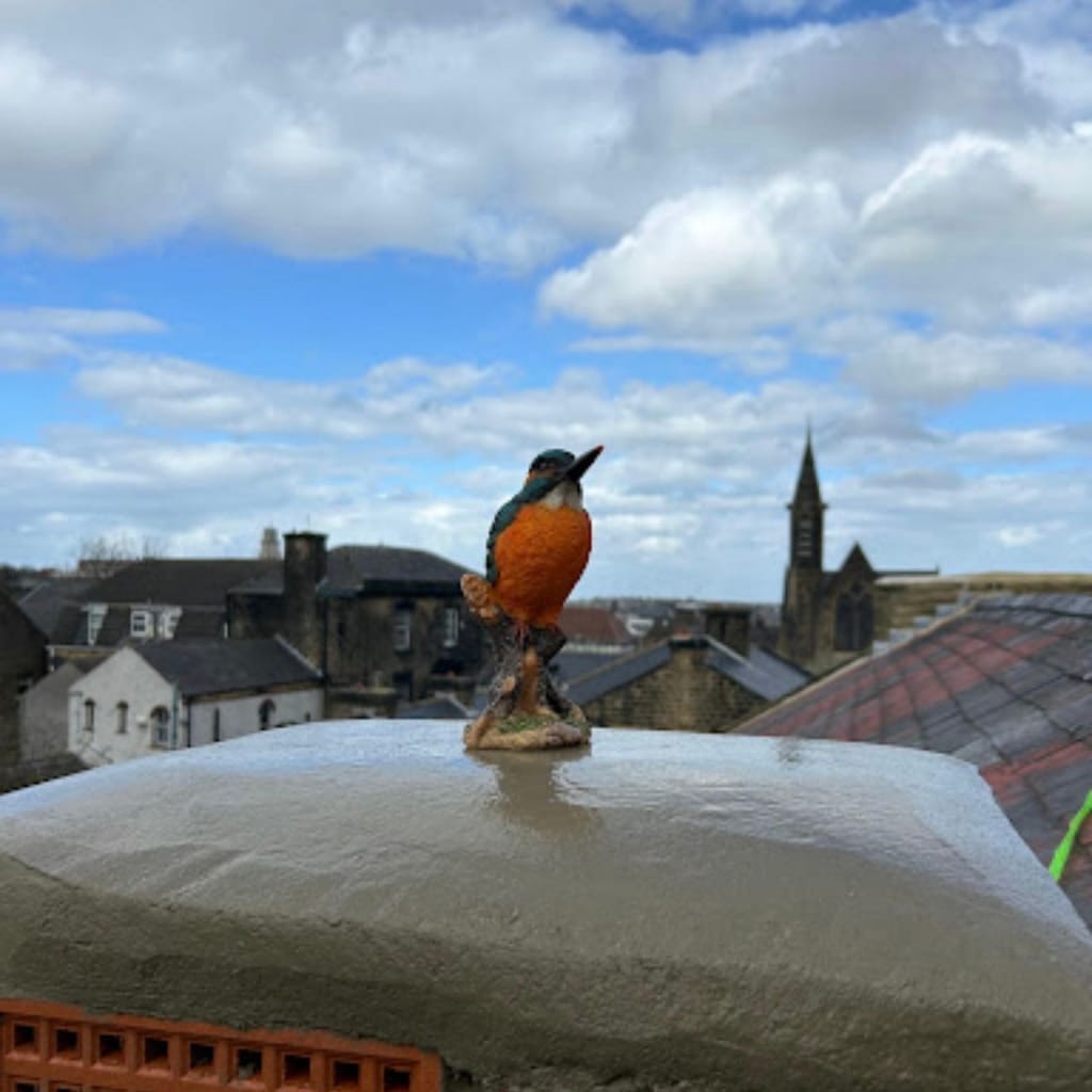 Small carved bird figurine perched on a freshly finished chimney cap