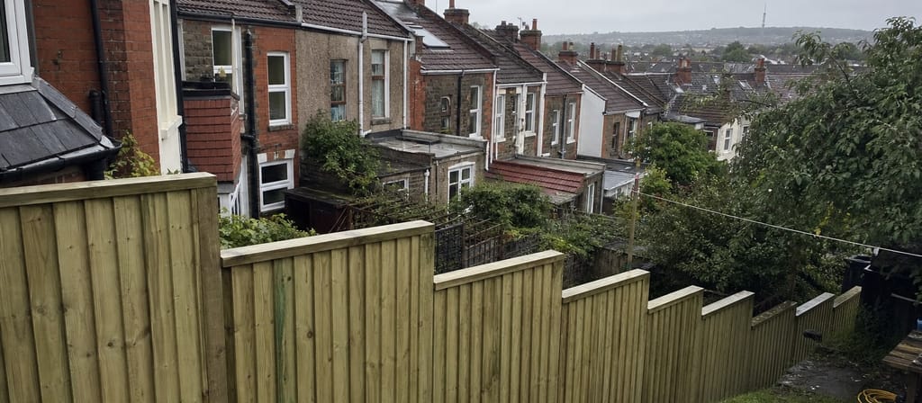 Sloping Victorian terrace gardens in Bishopston, a closeboard run stepped down the slope and the Purdown tower faint on the far skyline