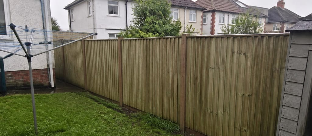 Post-war semi gardens in Fishponds, a plain closeboard boundary between two lawns with a rotary washing line beside it