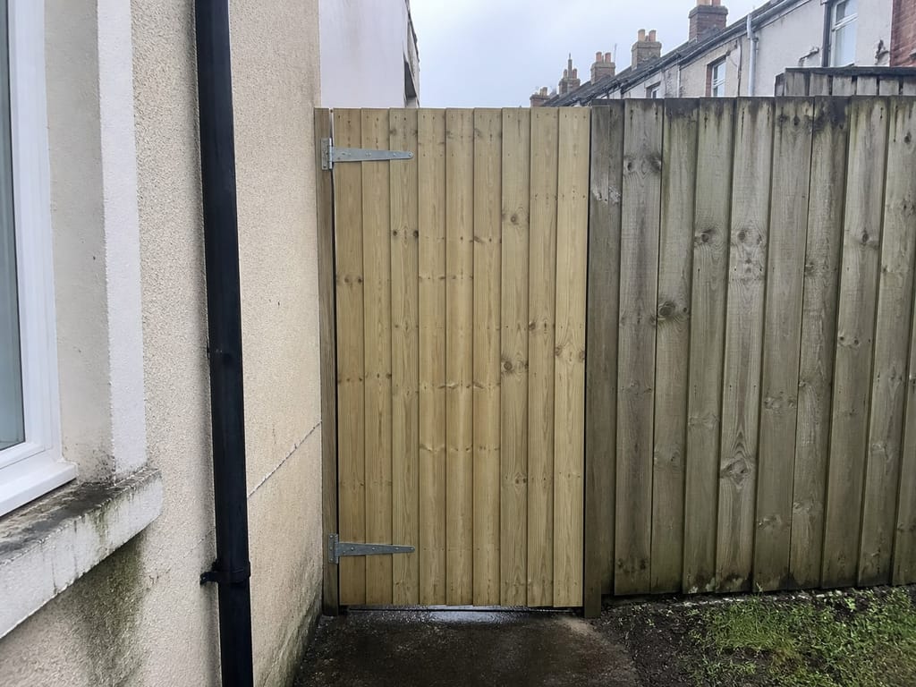 A side gate hung and squared to the opening, closing cleanly against the post with an even gap down the leading edge