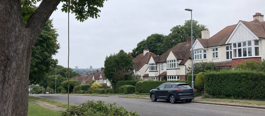 Interwar bay-fronted semis in Marshalswick seen across the rooftops, with the cathedral tower faint on the far skyline